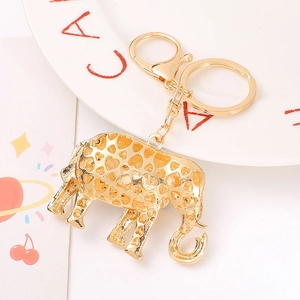 Golden elephant keychain with crystal rhinestones and heart pattern on white ceramic plate