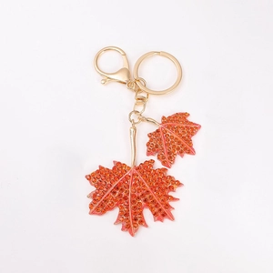 Porte-clés feuille d'érable dorée avec strass orange et fermoir mousqueton sur fond blanc