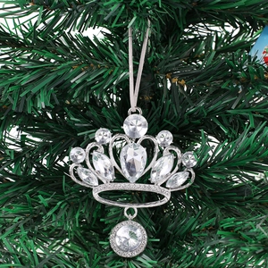 Elegant silver crown ornament with sparkling crystals hanging on a green Christmas tree