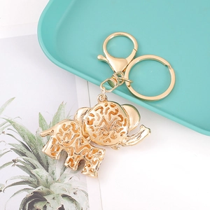 Elefant Schlüsselanhänger in Gold mit Kristallen und Hohlmuster auf grünem Tablett