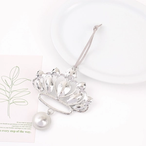 Silver crown hanging ornament with crystals and leather strap on a white surface