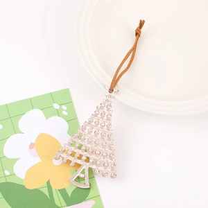Detail view of silver metal Christmas tree pendant with textured surface and brown cord