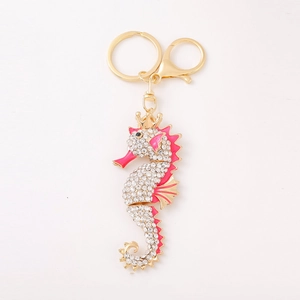 Golden seahorse keychain with sparkling rhinestones and pink enamel finish on white background