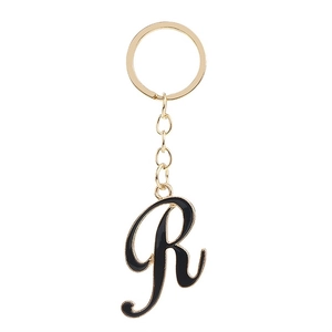 Golden keychain with artistic letter R in black enamel finish on white background