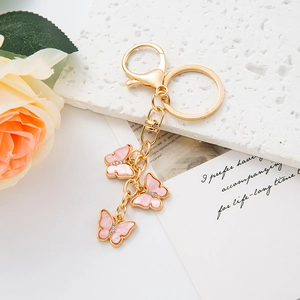 Detail of pink butterfly charms on gold keychain with rhinestones and shell-like texture