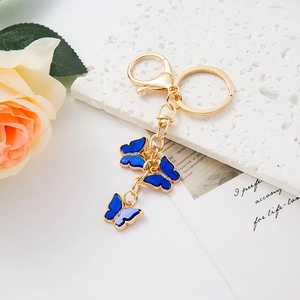 Close-up of golden keychain featuring three dark blue butterfly charms with small diamonds
