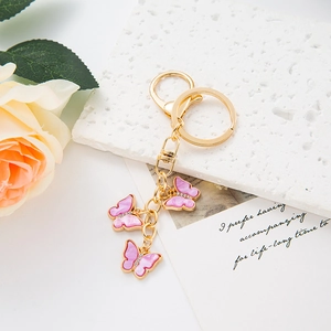 Detail of three pink enamel butterfly charms with gold keychain and lobster clasp