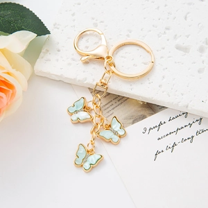 Detail of three light green butterfly pendants with rhinestones on a gold keychain