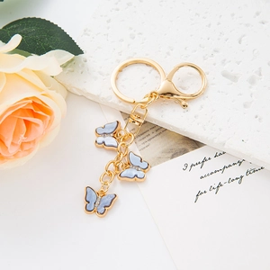 Detail of gold butterfly keychain with light blue marble texture and inset crystals