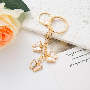 Detailed view of three golden butterfly charms with white shell texture and small crystals