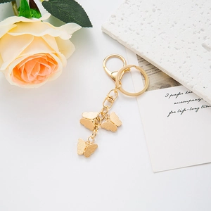 Detailed macro view of triple butterfly charms on a gold keychain with lobster clasp