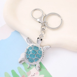 Dettaglio di un portachiavi a forma di tartaruga d'argento con strass azzurri scintillanti