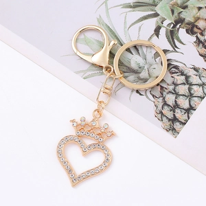 Detail of a golden heart crown keychain with sparkling rhinestones on a white background