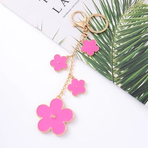 Detail of pink enamel flower keychain with gold chain and lobster clasp on white background