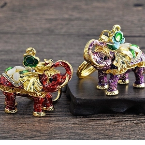 Exquisite enamel elephant keychains with gold plating and rhinestones on a wooden background