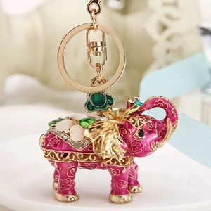 Close-up of pink enamel elephant keychain with gold cloud patterns and inlaid gemstones