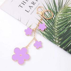 Detail of purple floral keychain with gold metal chain and lobster clasp on white background
