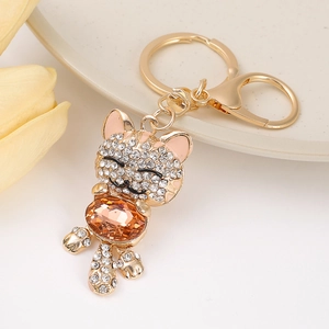Nahaufnahme der goldenen Katzen-Schlüsselanhänger mit weißen Kristallen und Bernstein