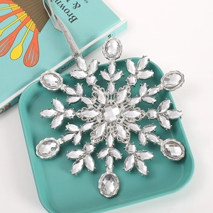 Detailed view of silver snowflake ornament with sparkling crystals on green tray