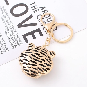 Detail of golden tiger head keychain with black stripes and sparkling rhinestone accents