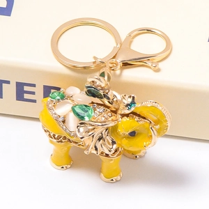 Detailed macro of golden elephant keychain with yellow enamel and green gemstones