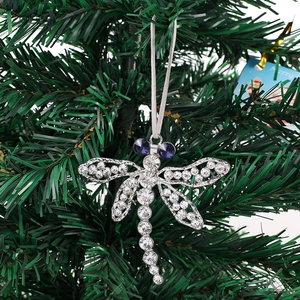 Sparkling dragonfly ornament with rhinestones hanging on a green Christmas tree branch