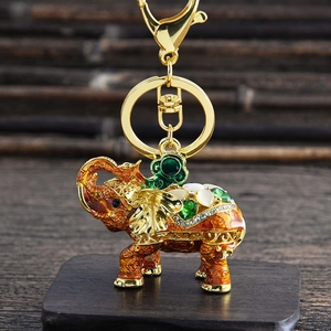 Detail of cute elephant keychain with orange enamel, gold plating and green crystals