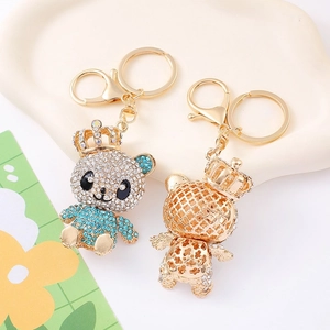 Sparkling crown bear keychain with blue and white crystals on a white ceramic tray