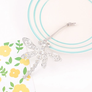 Detailed view of silver dragonfly ornament with hollow wings and grey velvet hanging cord