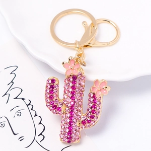 Golden cactus keychain with pink crystals and small flowers on white background