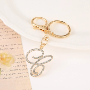 Detail of a sparkling gold letter keychain with crystal rhinestones on a white plate