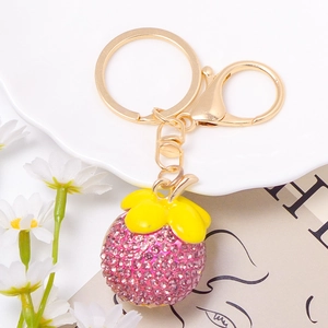 Cute pink rhinestone mangosteen keychain with gold alloy clasp on white ceramic plate