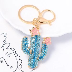 Detailed macro view of gold cactus keychain with blue rhinestones and pink enamel flowers