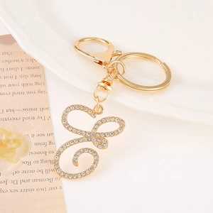 Macro view of gold-plated letter S keychain with sparkling white rhinestones on white plate