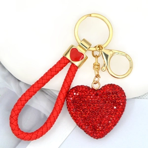 Dettaglio portachiavi a cuore con strass rossi e cinturino in pelle intrecciata rossa