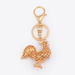 Detailed view of golden rooster keychain with hollow pattern and colorful cat eye stones