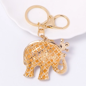 Golden elephant keychain with hollow pattern, lobster clasp and ring on ceramic tray