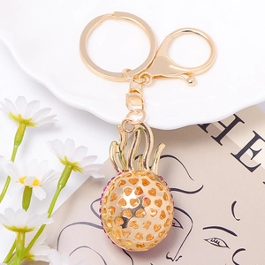 Detail of gold pineapple keychain with purple rhinestones and hollow heart design