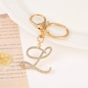 Close-up of golden letter L keychain with sparkling rhinestones on a vintage background