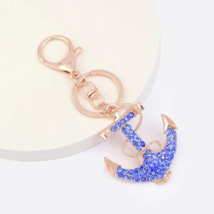 Détail du porte-clés ancre en or rose avec des strass bleu marine sertis avec précision