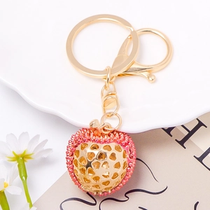 Detailed view of a durian-shaped gold keychain with pink rhinestones and heart cutouts