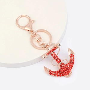 Détail du porte-clés ancre en or rose avec strass rouges et fermoir mousqueton