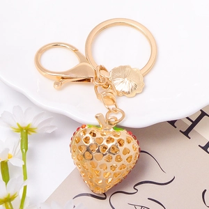 Detail of a gold strawberry keychain with hollow heart design and rhinestone accents