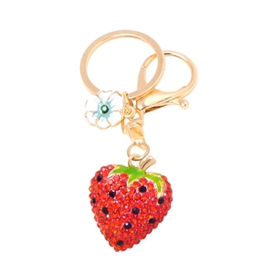 Detailed close-up of a cute strawberry keychain with sparkling red rhinestones and white flower