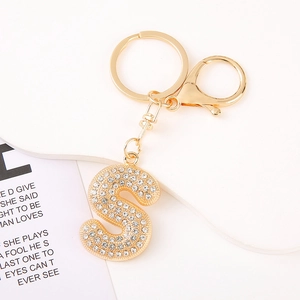 Detail of gold letter S keychain with crystal rhinestones on a white pedestal display