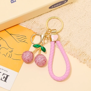 Dettaglio portachiavi a ciliegia rosa glitter con gancio dorato e cinturino in pelle