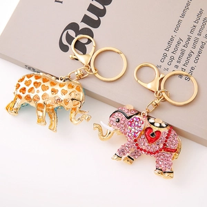 Glinsterende olifant sleutelhangers met roze strass en hartjes op een antiek boek