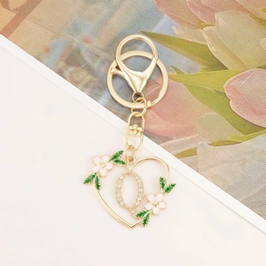 Close-up of heart-shaped letter Q keychain with pink enamel flowers and white rhinestones