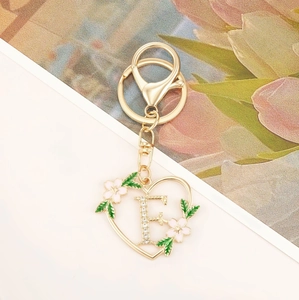 Detailed close-up of golden heart-shaped keychain with crystal-studded letter E and pink flowers
