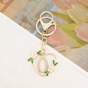 Detail of heart-shaped gold keychain with pink floral decor and sparkling rhinestones